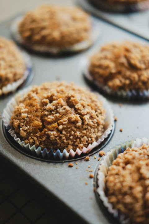 Freshly baked muffins with crumb topping in a metal tin