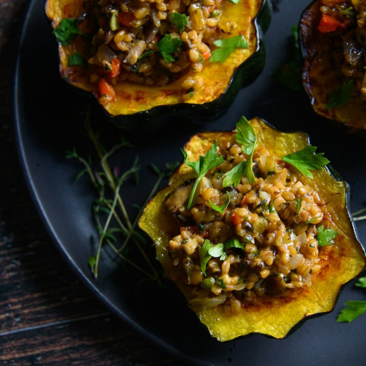 Baked acorn squash stuffed with a lentil, walnut and vegetable filling, served on a black plate