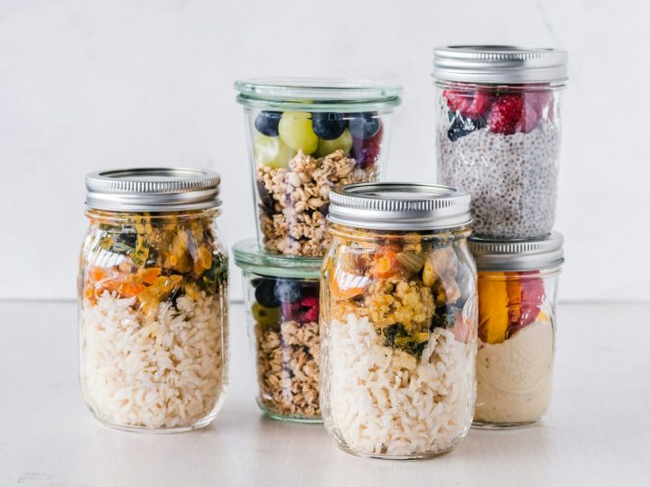 Six glass jars of prepped breakfast and lunch food lined up for the week