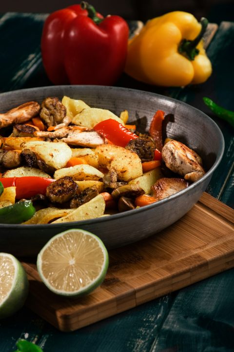 A pan filled with chicken and vegetables on a cutting board