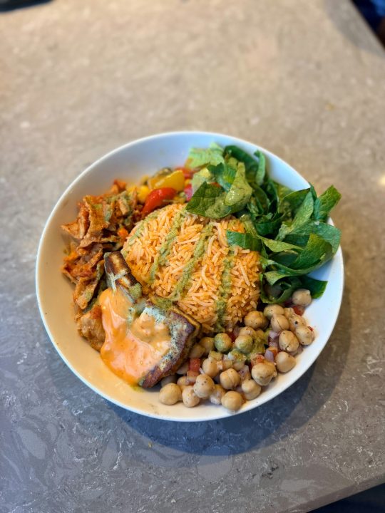 A colorful bowl of food with rice, chickpeas and greens