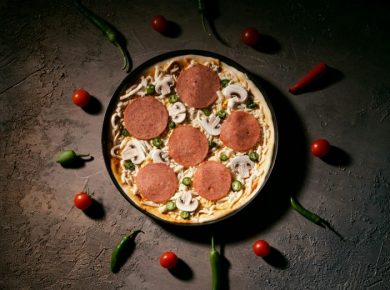 A pizza with pepperoni, mushrooms and peas surrounded by peppers