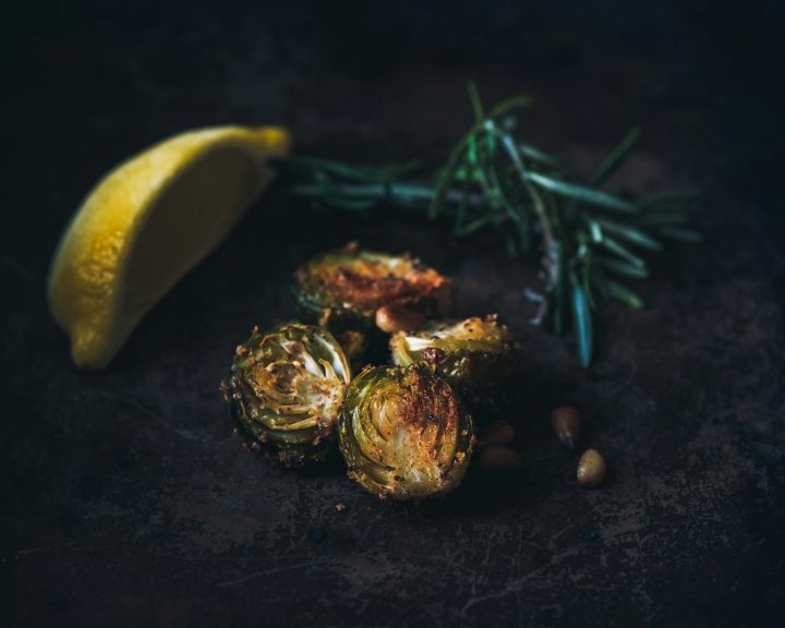 Crispy Brussels sprouts with a lemon wedge and a rosemary sprig