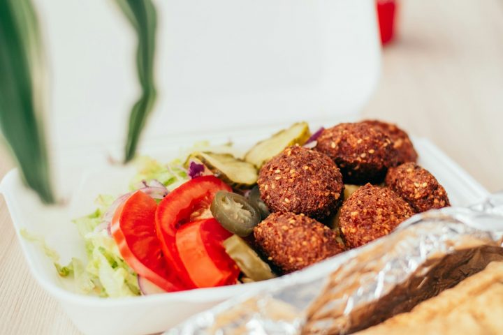 Falafel with salad and sliced tomatoes in a takeout box
