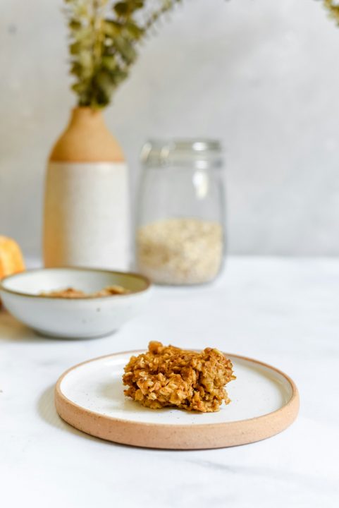 White plate topped with granola next to a vase of flowers