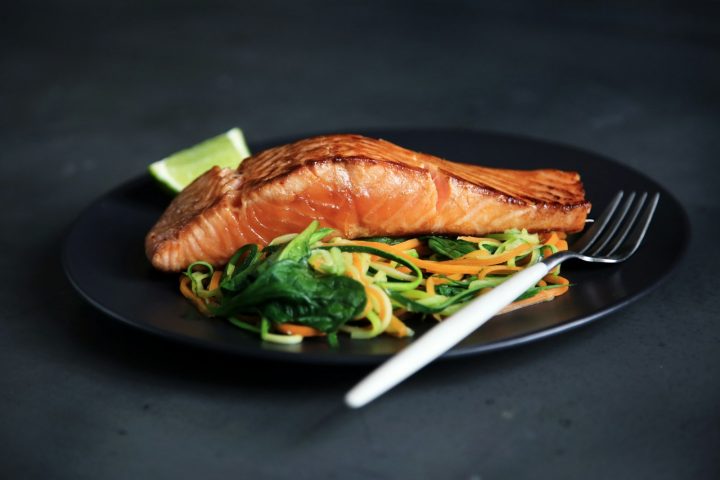 Grilled fish fillet with cooked vegetables on a plate with a fork