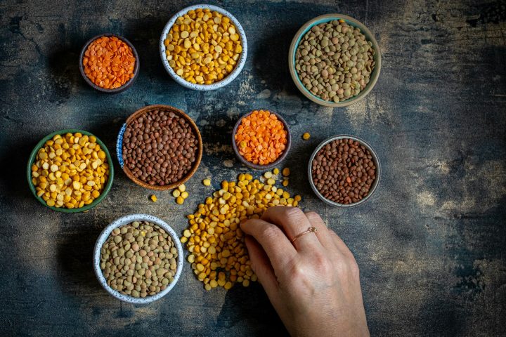 Different kinds of dried lentils in bowls on a table