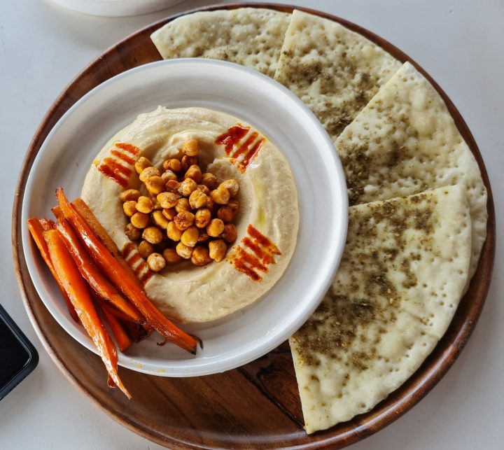 A plate of hummus with carrots and pita bread, the base for a Halloween veggie tray