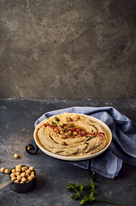 A bowl of hummus with whole chickpeas on the side