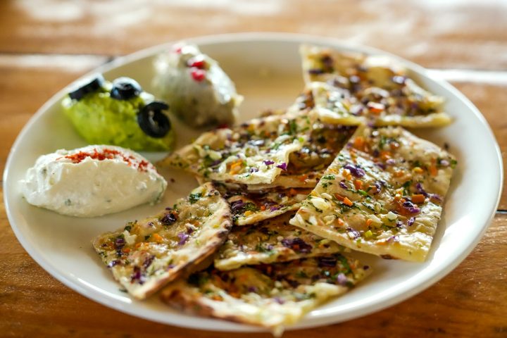 Flatbread with dips, olives and fresh toppings on a mezze plate