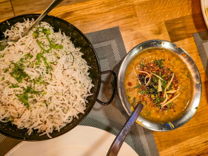 A bowl of basmati rice next to a bowl of cooked lentils on a wooden table