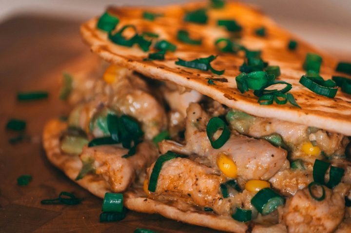 A freshly made burrito wrapped and resting on a wooden surface