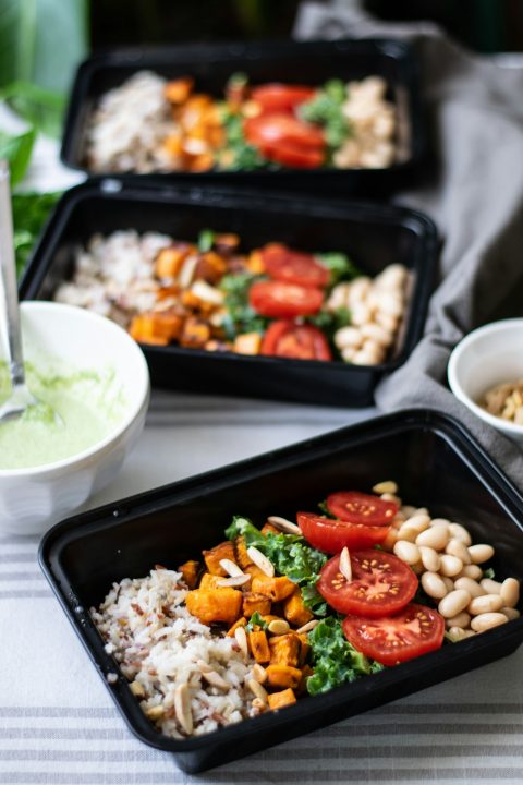 Two meal prep trays with healthy grain bowl lunches