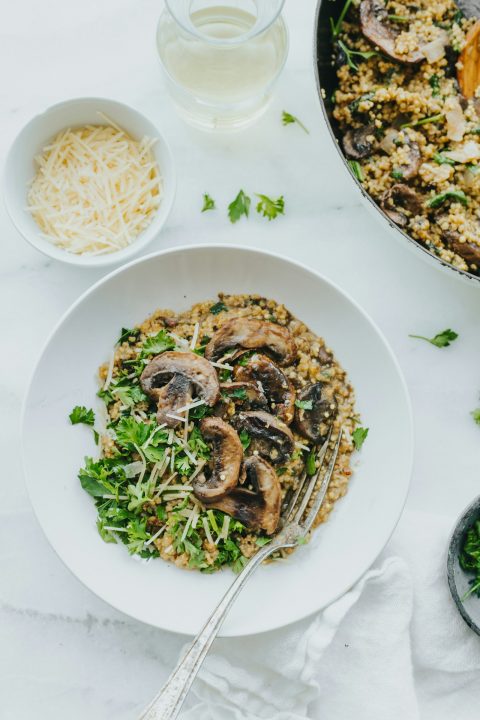 A bowl of mushroom risotto topped with fresh parsley and shredded parmesan cheese