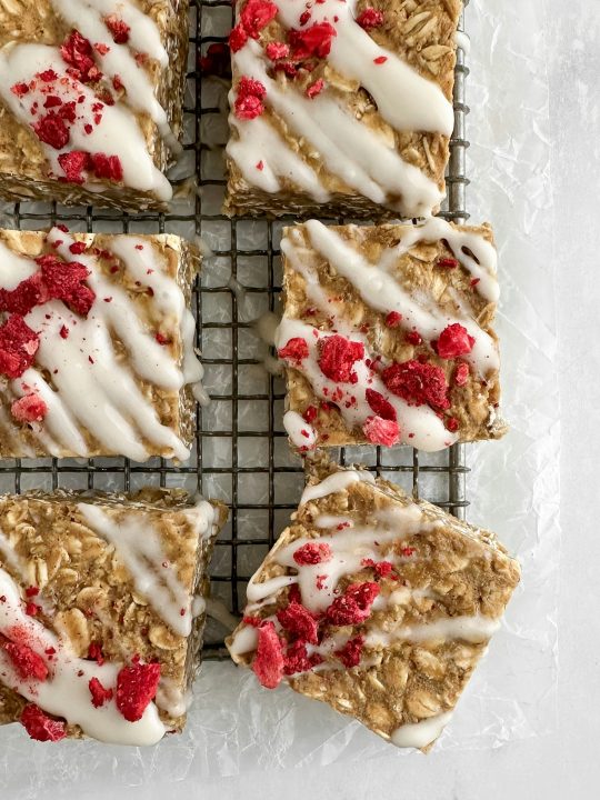 Oat bars with a vanilla glaze and crushed freeze-dried berries on a wire rack