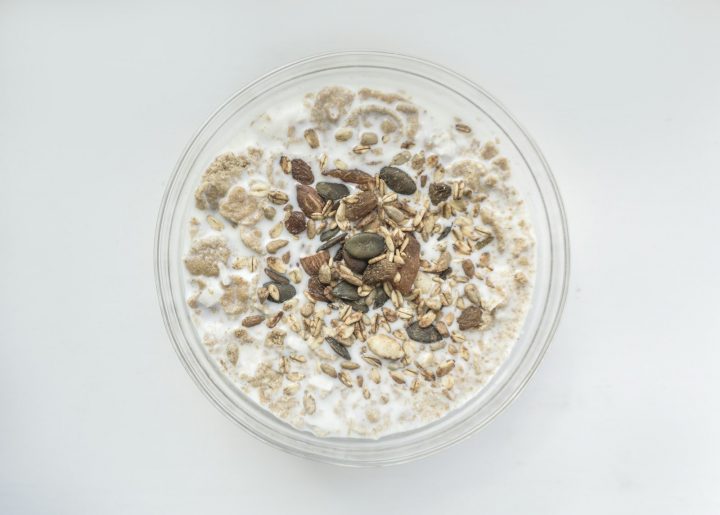 A bowl of oatmeal breakfast topped with seeds and almonds