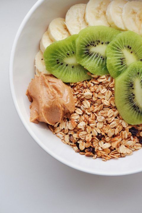 A bowl filled with oats, kiwi and peanut butter