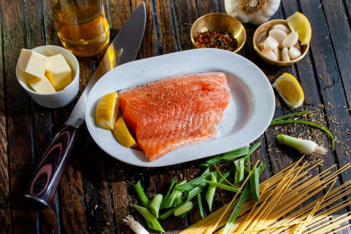 Flat lay of a raw salmon fillet with ingredients for meal preparation