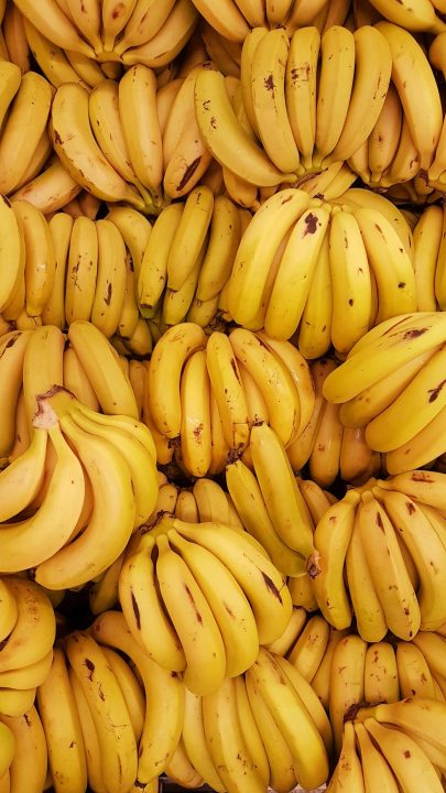 Clusters of ripe yellow bananas with brown spots packed together
