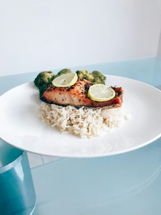 A white plate topped with rice and a piece of cooked salmon