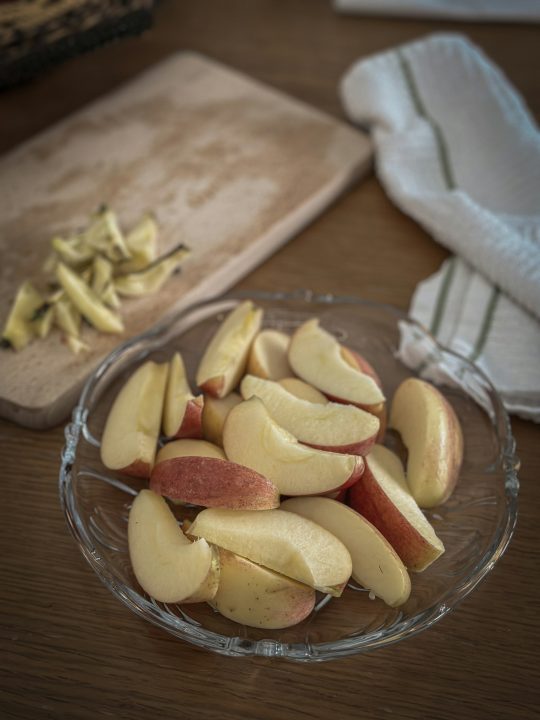 A glass bowl filled with sliced apples on a table