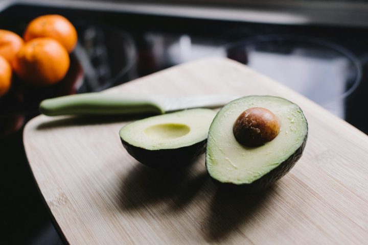 Sliced avocado on a brown wooden chopping board