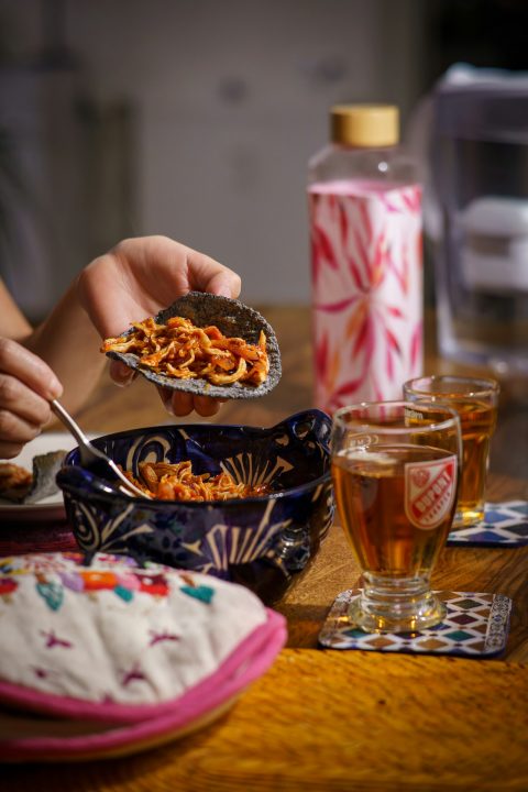 Person filling a taco with food from a bowl