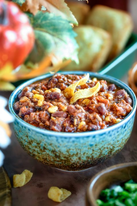 A bowl of chili on a table next to other bowls of food