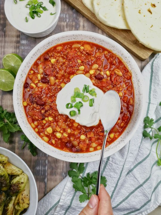 A bowl of chili with sour cream on top
